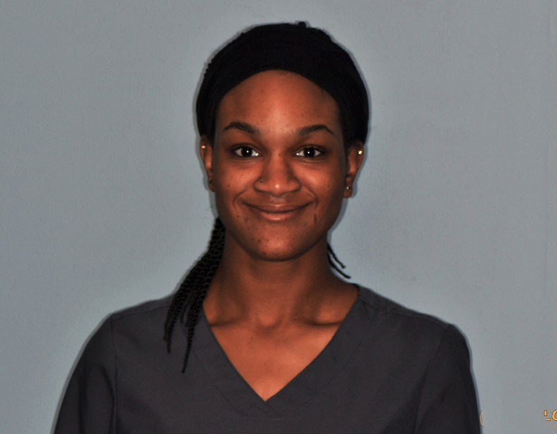 Portrait of Paris, smiling dental assistant in uniform against a plain background